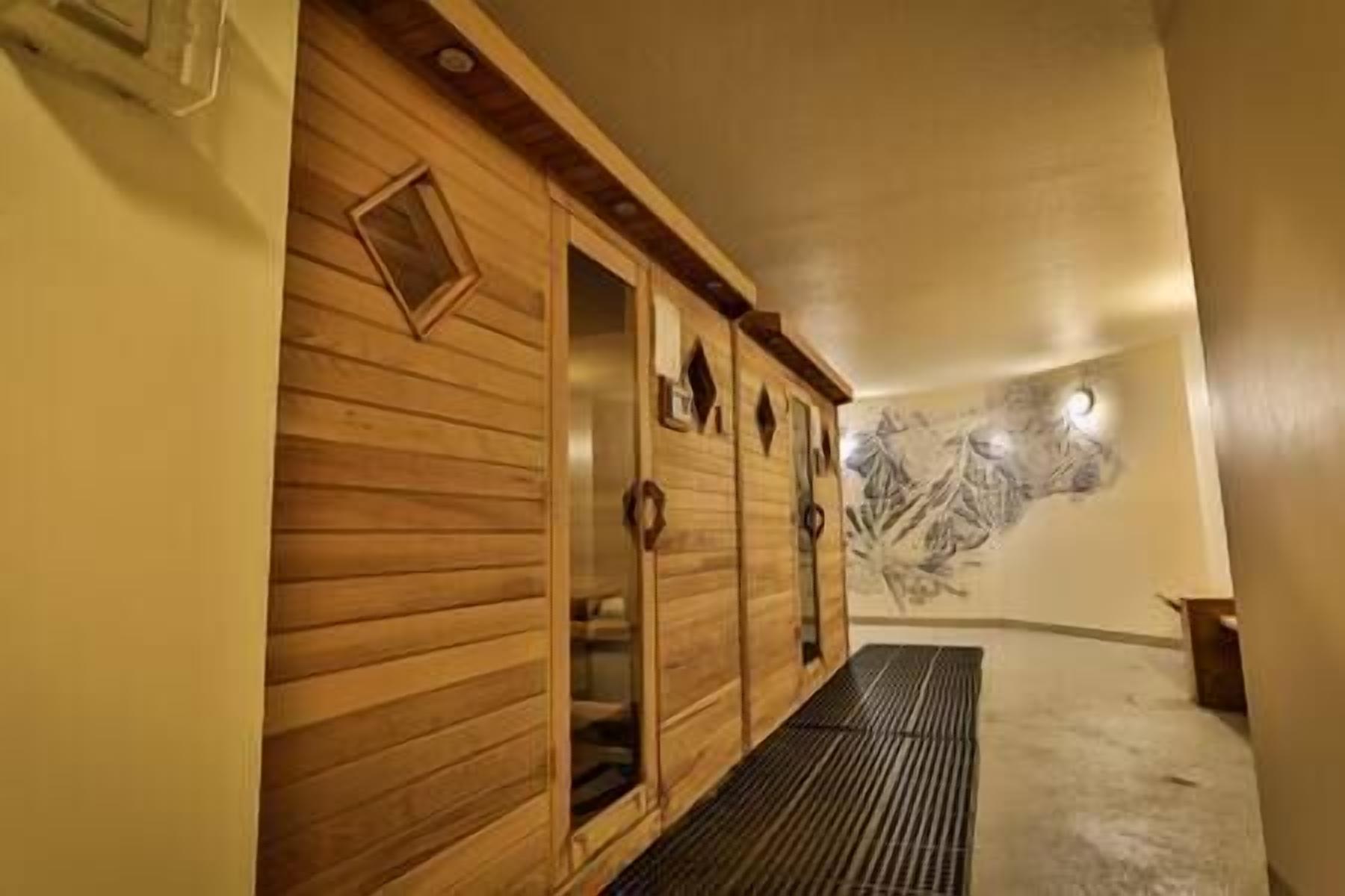 Une armoire en bois avec une porte miroir, un luminaire fixé au mur et un mur à texture.