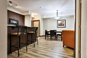 Una cocina compacta con microondas, taburetes de bar y una mesa de comedor con sillas.