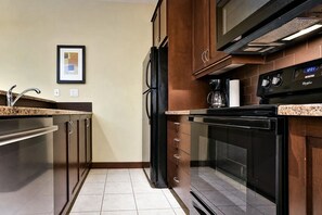 Une cuisine moderne dotée d’appareils électroménagers en acier inoxydable, de meubles en bois et d’un sol carrelé.