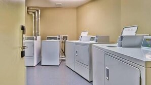 A laundry room with multiple washing machines and dryers, a control panel, and a tiled floor. - 1 BDRM / King / AC / Hot Tub & Pool (Fernie)