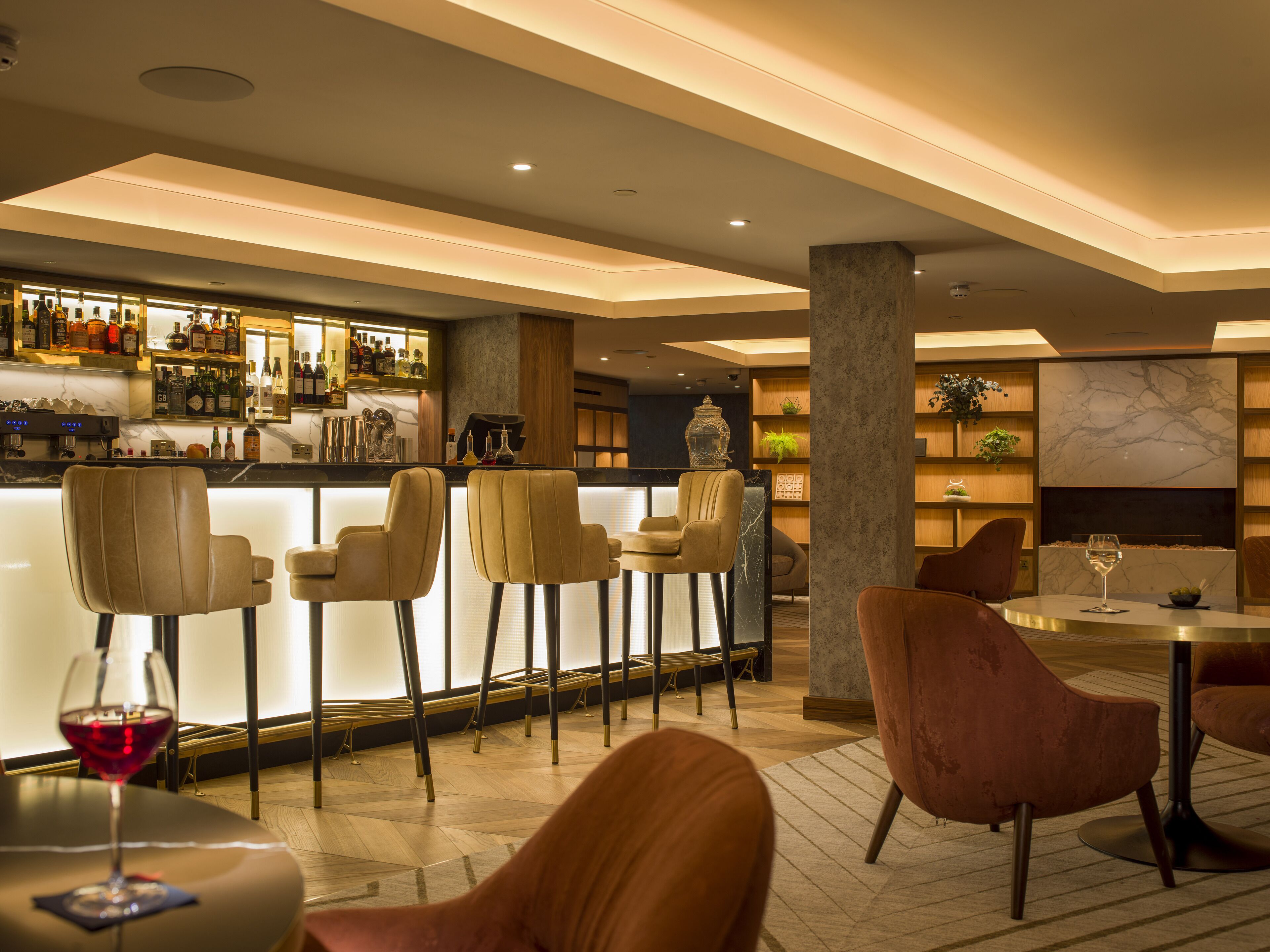 A bar area with seating, a bar counter with bottles, and a fireplace.