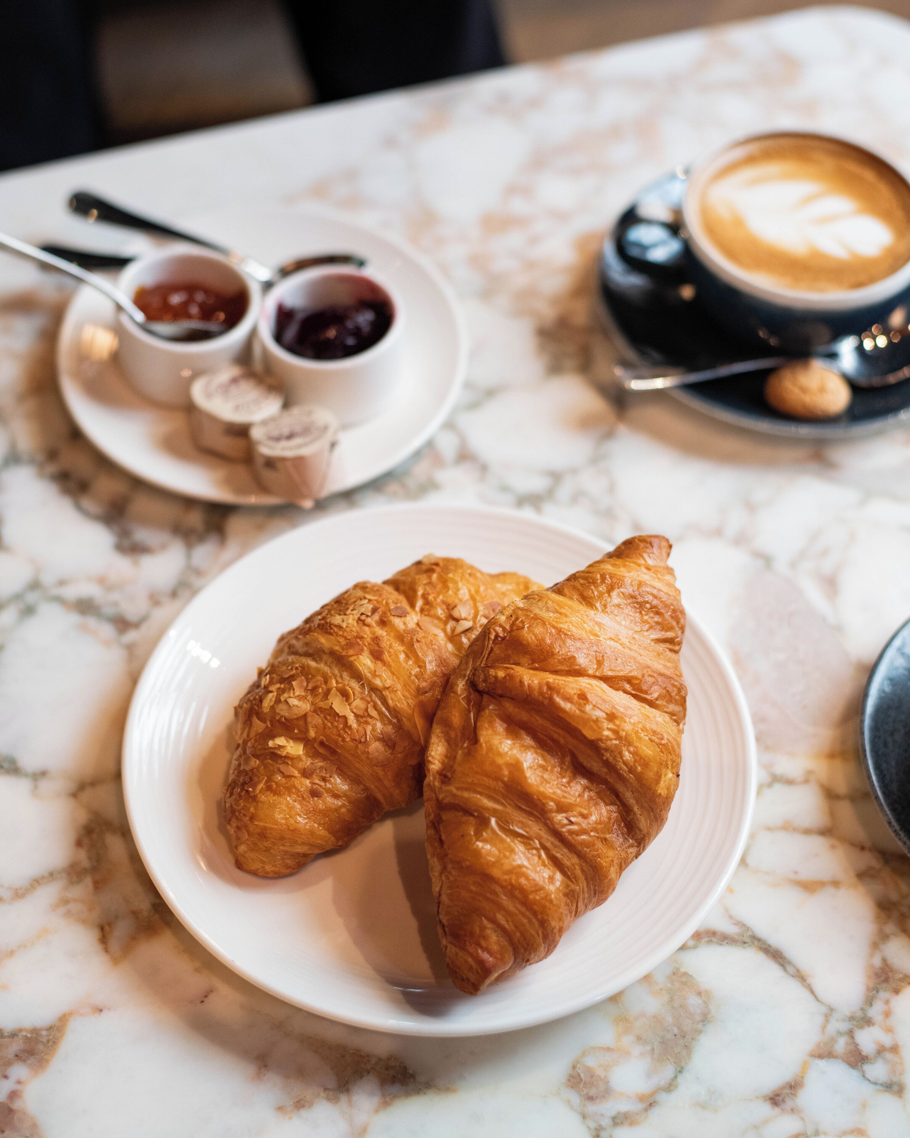Una mesa de mármol con una bandeja de cruasanes y una taza de café.