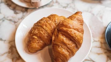 Una mesa de mármol con una bandeja de cruasanes y una taza de café.