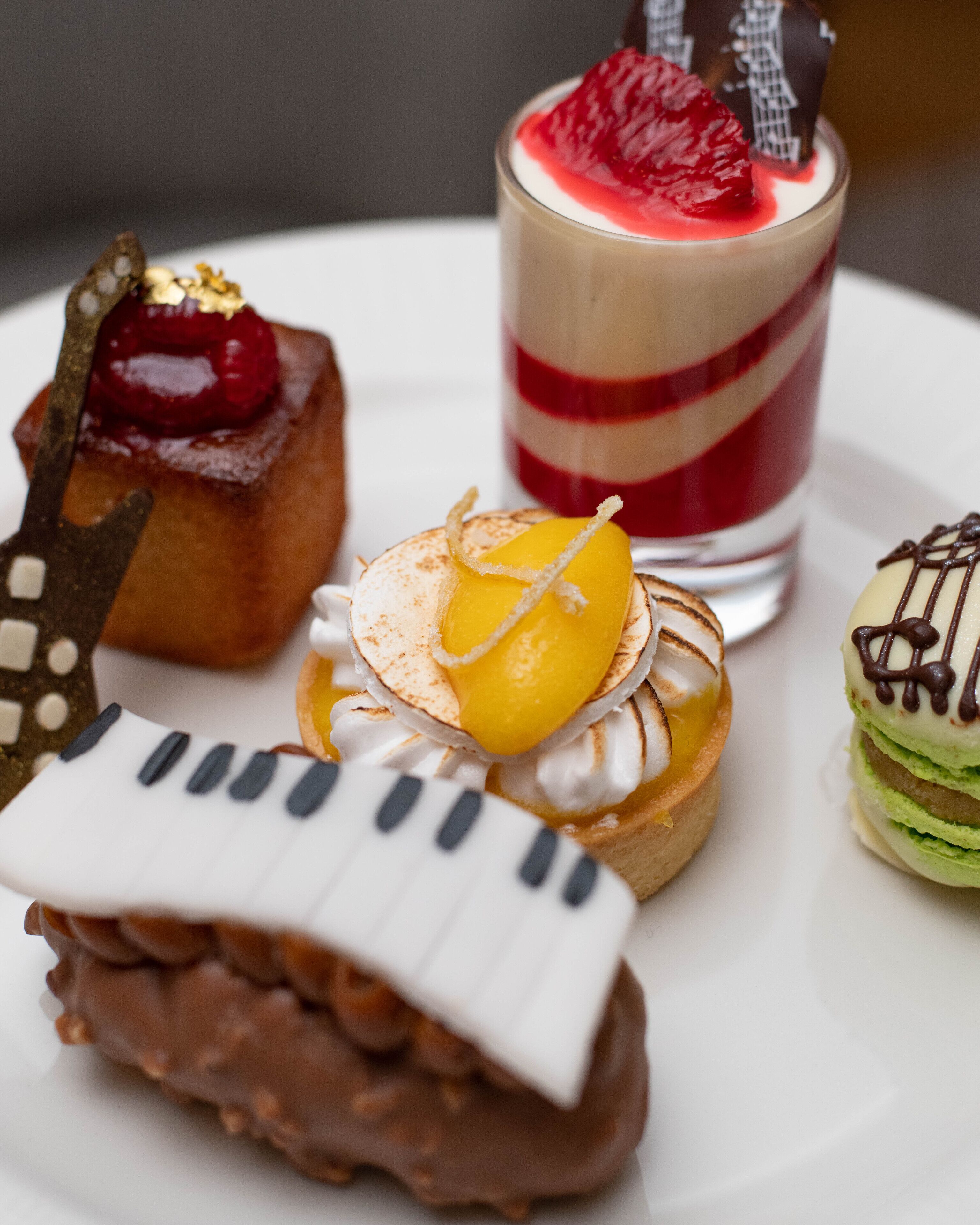 Ein Dessertteller mit verschiedenen Backwaren und einem Glas mehrschichtigem Dessert.