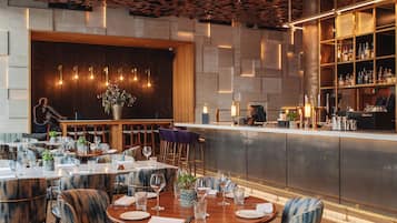 A restaurant with round tables, chairs, a bar area, and a ceiling with leaf patterns.