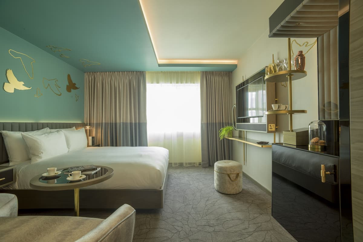 Een moderne hotelkamer met een groot bed, een zithoek met een salontafel, een televisie en een minibar.