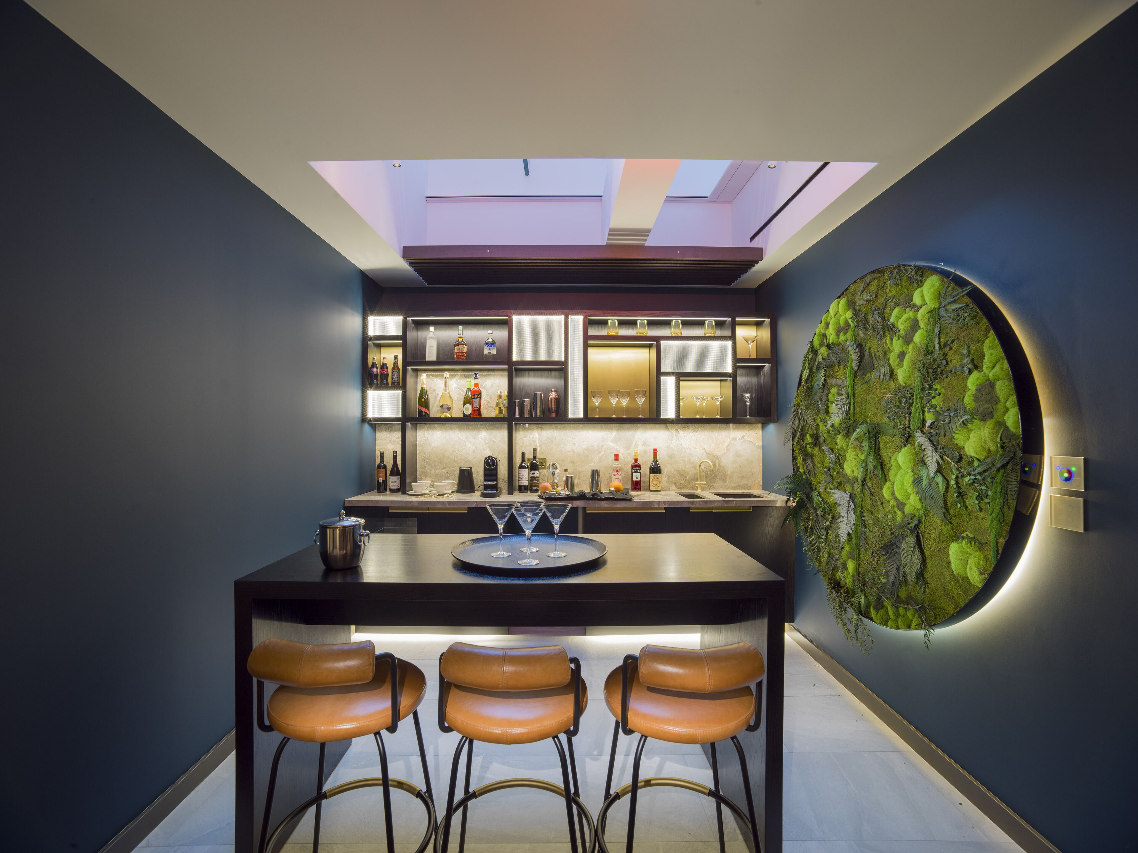 Una cucina moderna con isola centrale, sgabelli da bar e un’originale parete circolare.