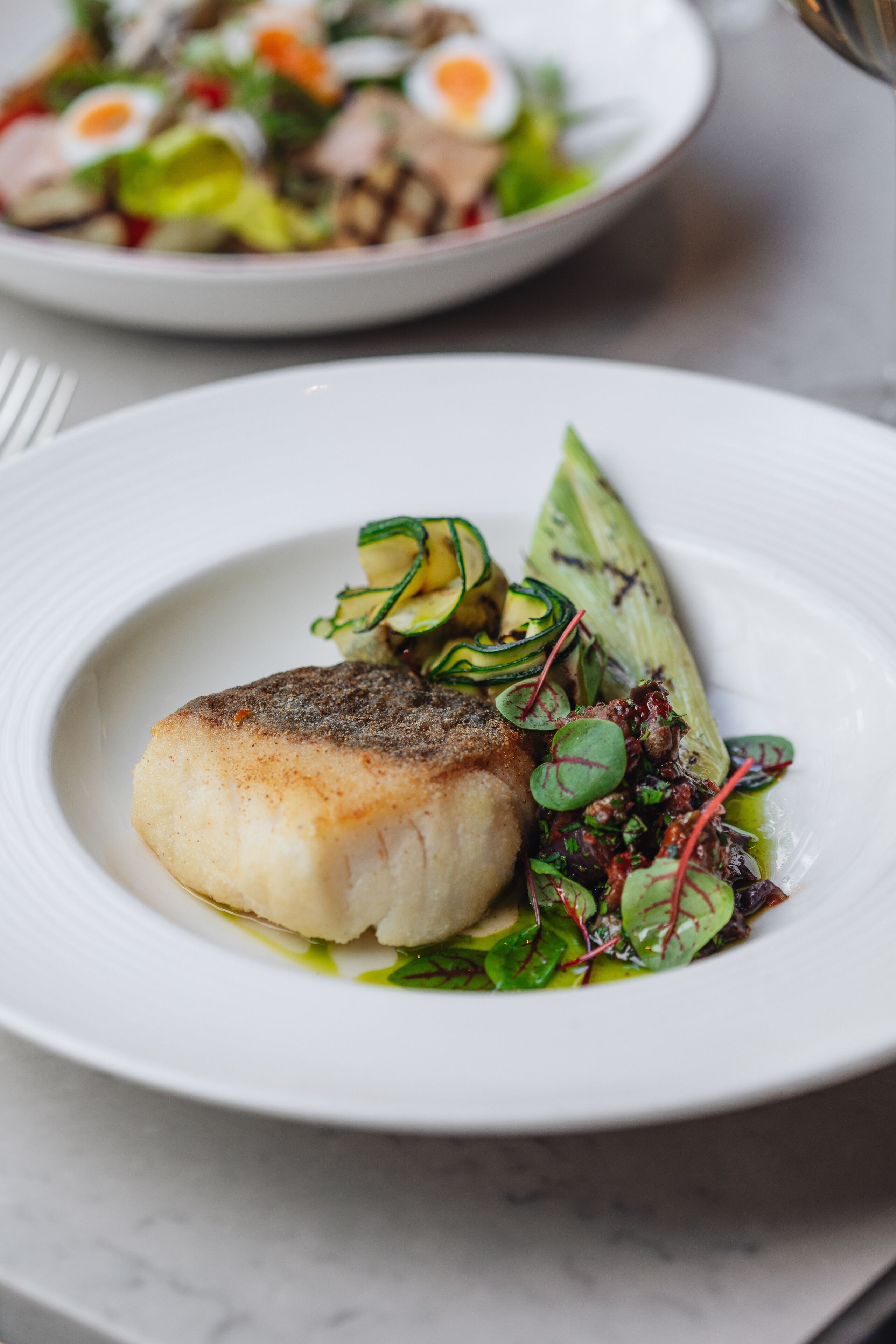 A plate of food with a piece of fish and vegetables.