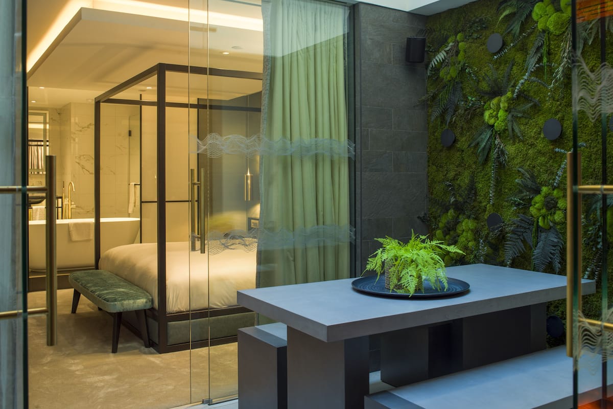 Een moderne badkamer met een douchecabine van glas, een bankje en een wastafel aan de muur.