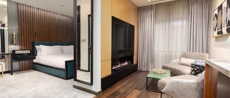 Un dormitorio moderno con cama, televisor, sofá y mesa de centro.