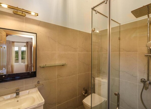 Baño con cabina de ducha de vidrio, lavamanos e inodoro.