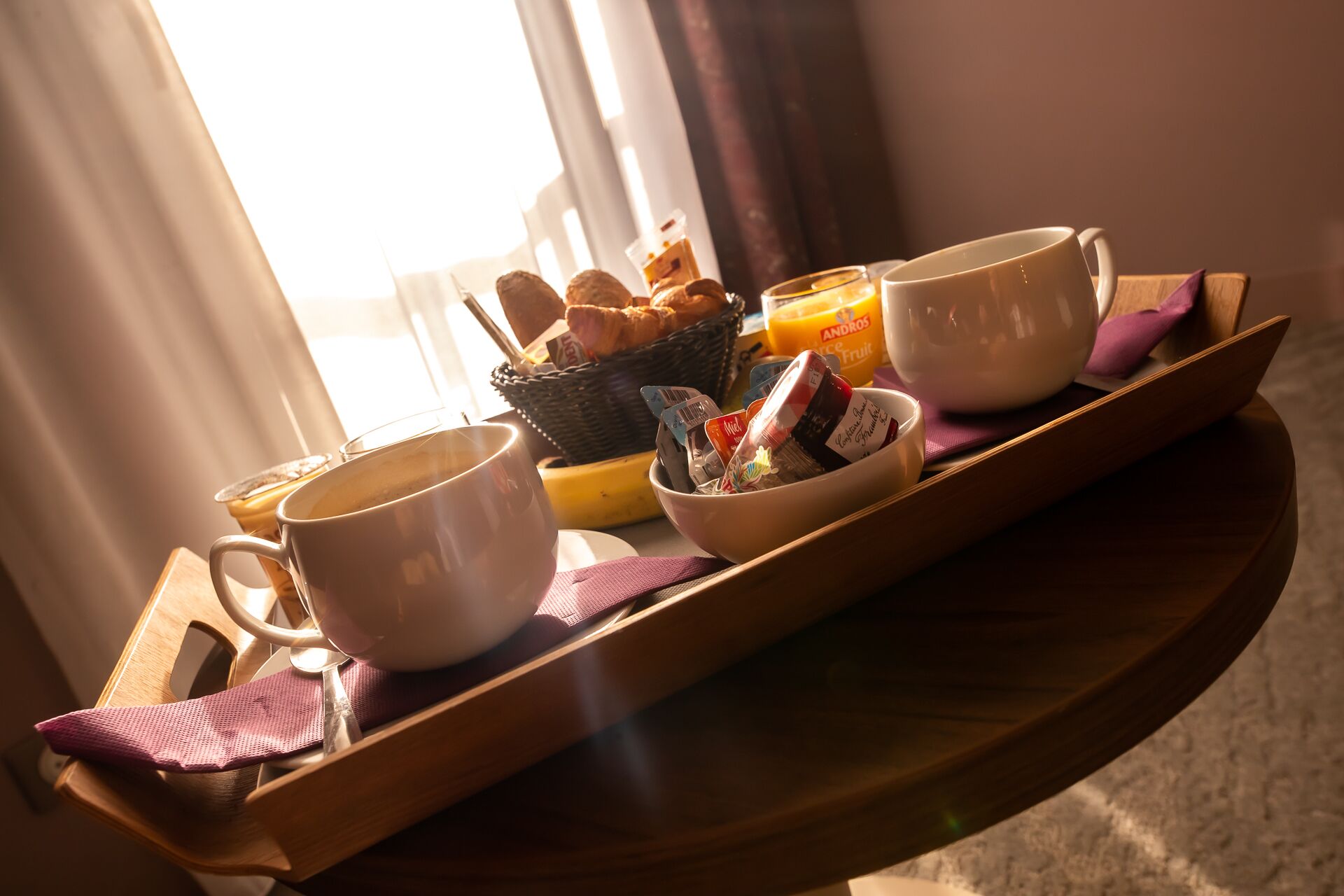 A breakfast tray with a bowl of cereal, a mug, a cup, and a bottle of orange juice.