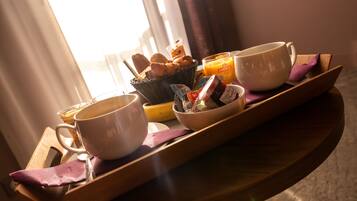 A breakfast tray with a bowl of cereal, a mug, a cup, and a bottle of orange juice.
