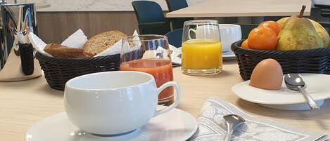 A breakfast setting with a cup, toast, juice, and fruit on a table.