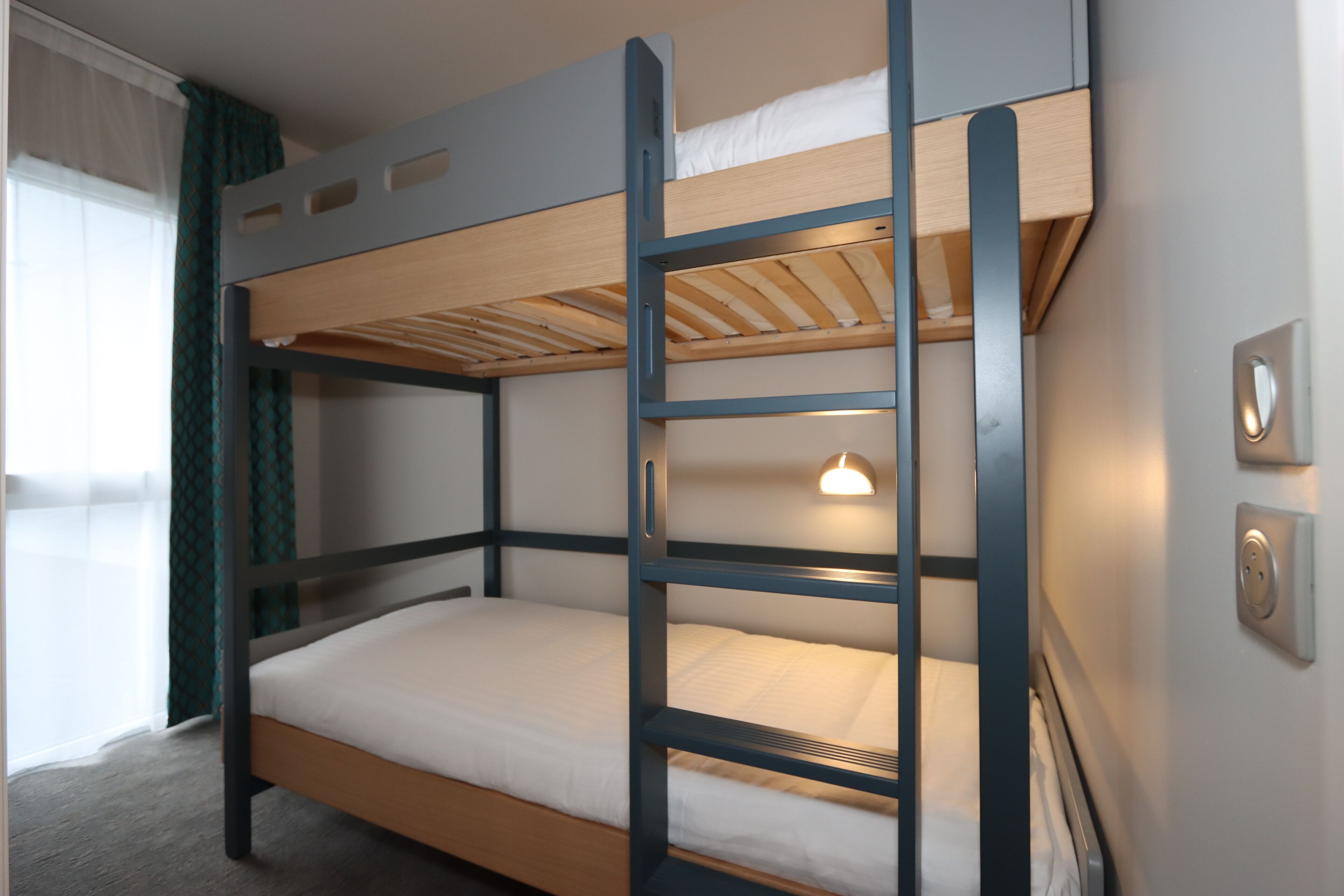 Un lit superposé avec une structure en bois et du linge de lit blanc.