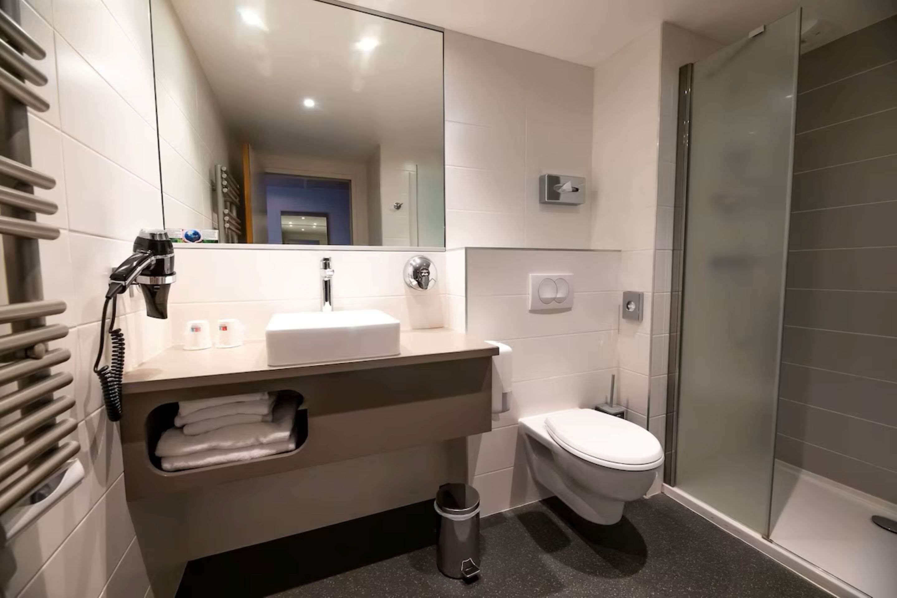 A modern bathroom with a sink, mirror, and toilet.