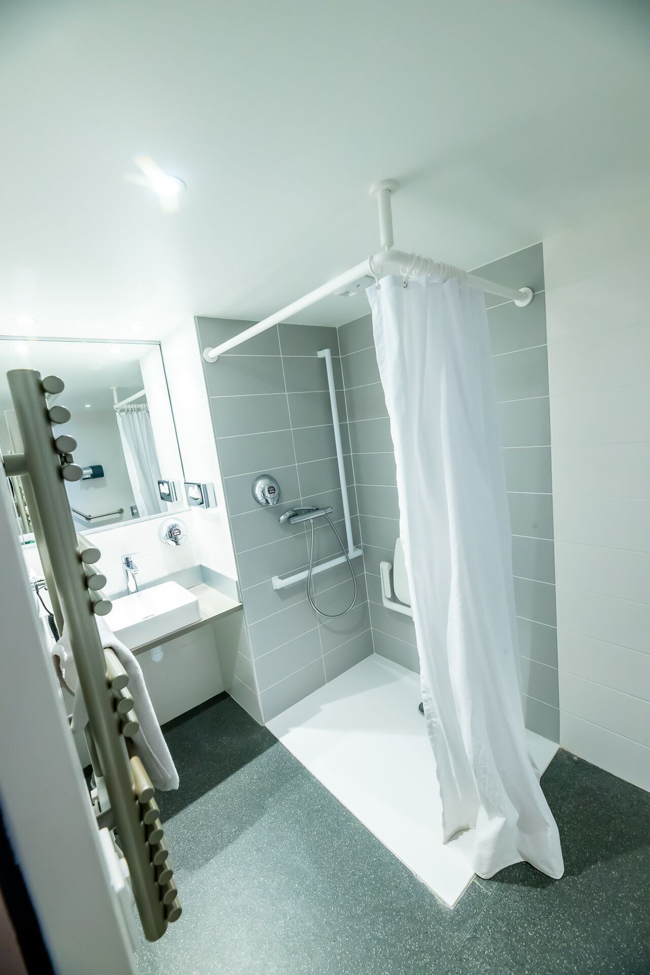Een moderne badkamer met een douchecabine van glas, een wastafel met spiegel en een witte wasbak.