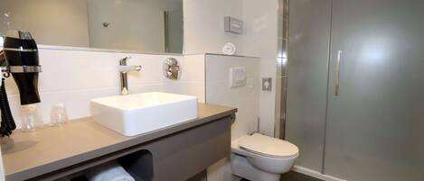A modern bathroom with a white sink, a toilet, and a glass shower enclosure.