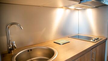Une cuisine moderne dotée d’un évier en acier inoxydable, d’un plan de travail en bois et d’armoires encastrées.