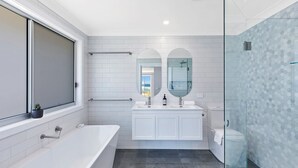Ein modernes Badezimmer mit Badewanne, einer Duschkabine aus Glas und einem großen Fenster.