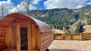 A wooden cabin with a curved roof, a wooden bench, and a view of a forested mountain range. - Stunning Chalet for 13 - Spacious Living Area, 4 Bedrooms, Garage, WIFI - La Clusaz (La Clusaz)