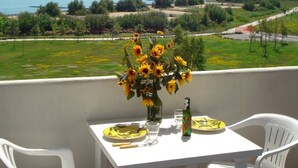 A balcony with a table set for two, overlooking a coastal landscape with a clear view of the sea and greenery. - Welcoming flat with large balcony (Porto Santa Margherita)