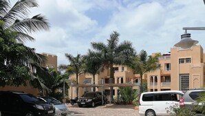 A paved driveway leading to a building with multiple balconies and palm trees. - Sea La Vie (Mombasa)