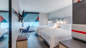 A modern hotel room with two beds, a desk, and a chair. There is a window with a geometric view, and a red stripe on the headboard. - avid hotel Zeeland - Holland by IHG (Zeeland)