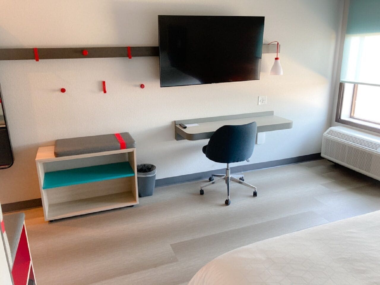 Una habitación de hotel moderna con cama, escritorio, silla, televisión y ventana.