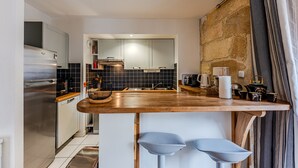 A modern kitchen with a wooden countertop, stainless steel appliances, and a stone accent wall. - Place du Palais Historic Center (Burdeos)