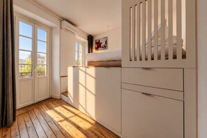 Una habitación con cama, armario y ventana con vistas a edificios.