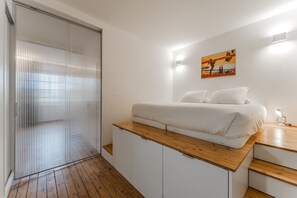 A bedroom with a bed, a wooden desk, a painting on the wall, and a sliding door. - Bordeaux historic center, A-C, Terrace & Parking (Burdeos)