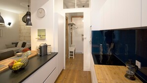A modern kitchen with white cabinets, a wooden countertop, and a black backsplash. - Luxury and comfort in the historic center of Bordeaux (Burdeos)