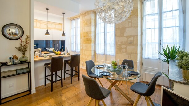 A modern kitchen with a dining area, featuring a glass table, chairs, and a unique chandelier. - Luxury and comfort in the historic center of Bordeaux (Burdeos)