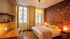 A bedroom with a bed, bedside table, lamp, and a wall with a mosaic pattern. - Luxury and comfort in the historic center of Bordeaux (Burdeos)