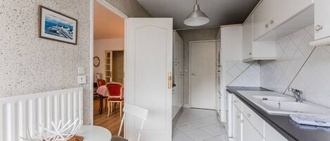 A modern kitchen with white cabinetry, a black countertop, and a white chair.