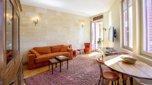 A living room with a sofa, coffee table, and a dining table with chairs. - Historic center, air-conditioned with terrace (Burdeos)