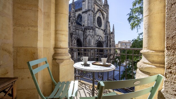 A balcony with two chairs and a table, overlooking a historic cathedral. - Historic center, air-conditioned with terrace (Burdeos)