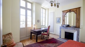 A bedroom with a bed, a desk, a chair, a fireplace, and large windows. - Historic center, air-conditioned with terrace (Burdeos)