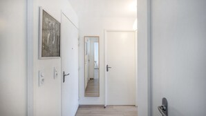 En smal hall med vita väggar, ett trägolv och en dörr längst ner.