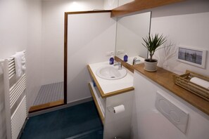 Une salle de bain moderne avec un lavabo blanc, un plan de travail en bois et une plante en pot.