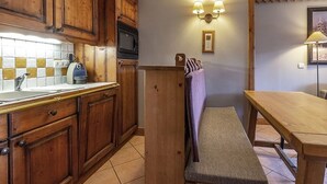 Una cucina con mobili in legno, un forno a microonde, un lavello e una panca.