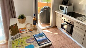A modern kitchen with a built-in oven, microwave, and a small island with a sink. - L'AMPHITHÉÂTRE, 3-room air-conditioned apartment, terrace, swimming pool & parking lot (Fréjus)