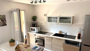 A modern kitchen with a microwave, toaster, and kettle on the countertop, a sink, and a refrigerator. - L'AMPHITHÉÂTRE, 3-room air-conditioned apartment, terrace, swimming pool & parking lot (Fréjus)