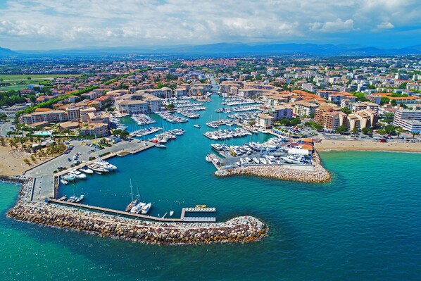 An aerial view of a marina with numerous boats docked, surrounded by residential buildings and a clear sky. - L'AMPHITHÉÂTRE, 3-bedroom air-conditioned apartment, terrace, swimming pool, and parking space (Fréjus)
