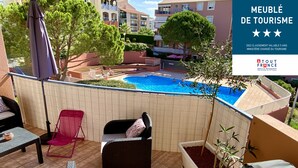A rooftop terrace with outdoor furniture, a swimming pool, and a view of surrounding buildings. - L'AMPHITHÉÂTRE, 3-room air-conditioned apartment, terrace, swimming pool & parking lot (Fréjus)