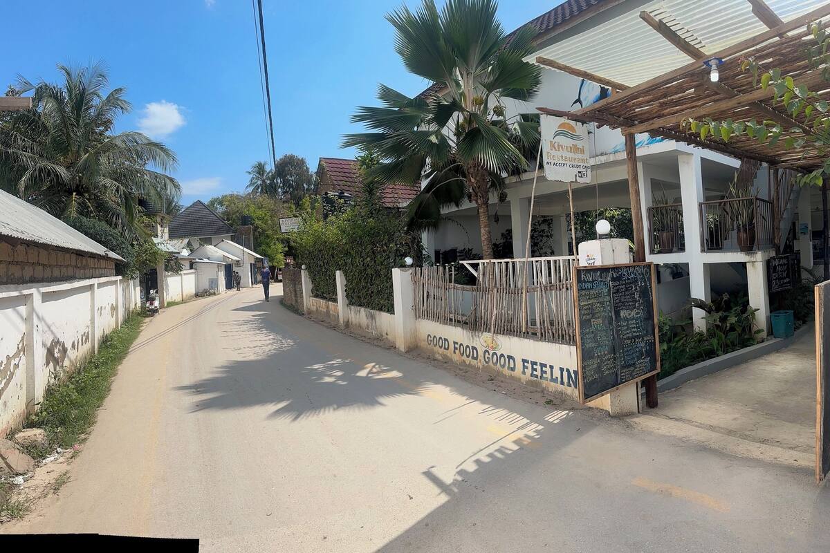 A street leading to a restaurant with a signboard listing menu items and prices.