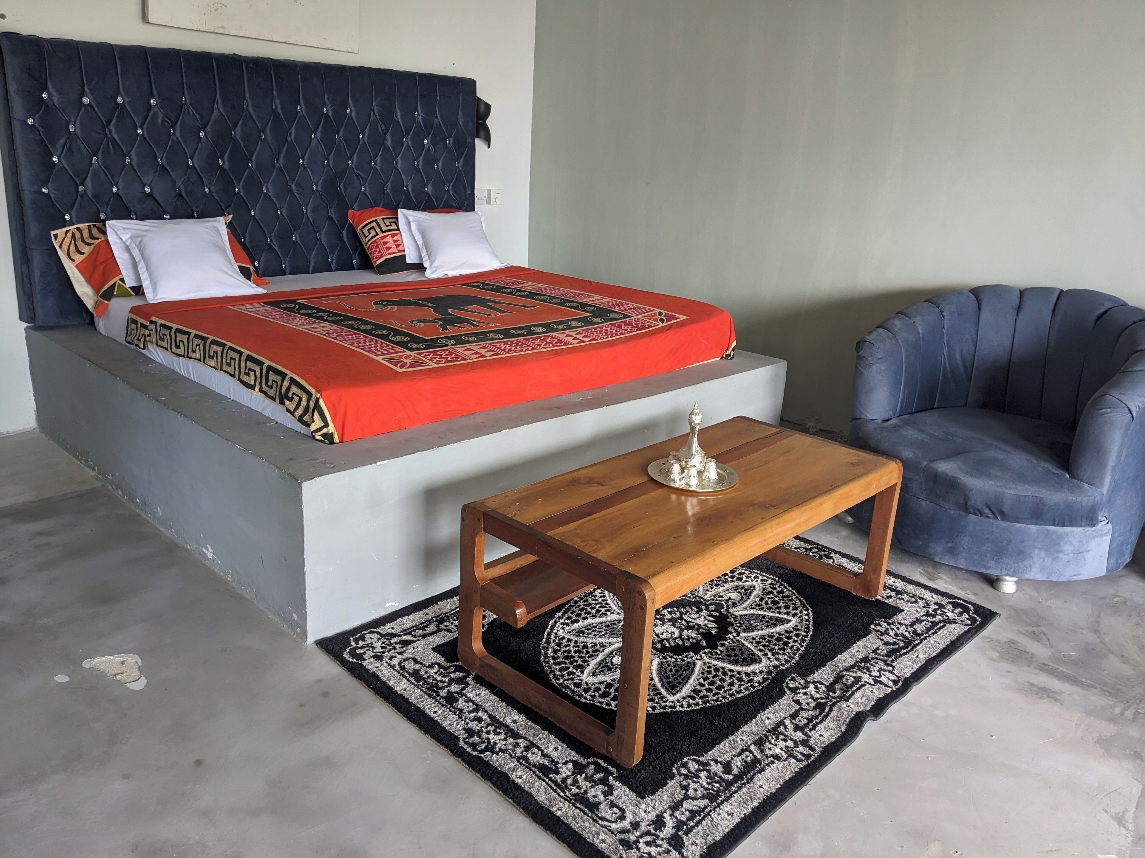 A bedroom with a bed, a bedside table, a chair, and a decorative tray.