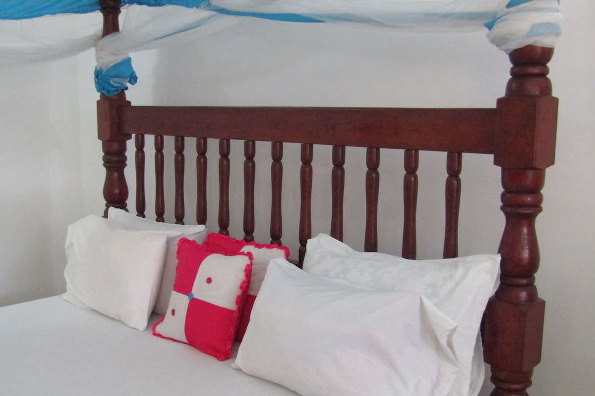 Una cama con cabecera de madera y ropa de cama blanca.