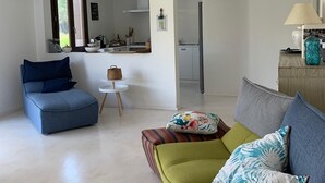 A modern living room with a sofa, a chair, a small table, and a kitchen area visible through an open door. - Exclusive Farm (S'arena Scoada)